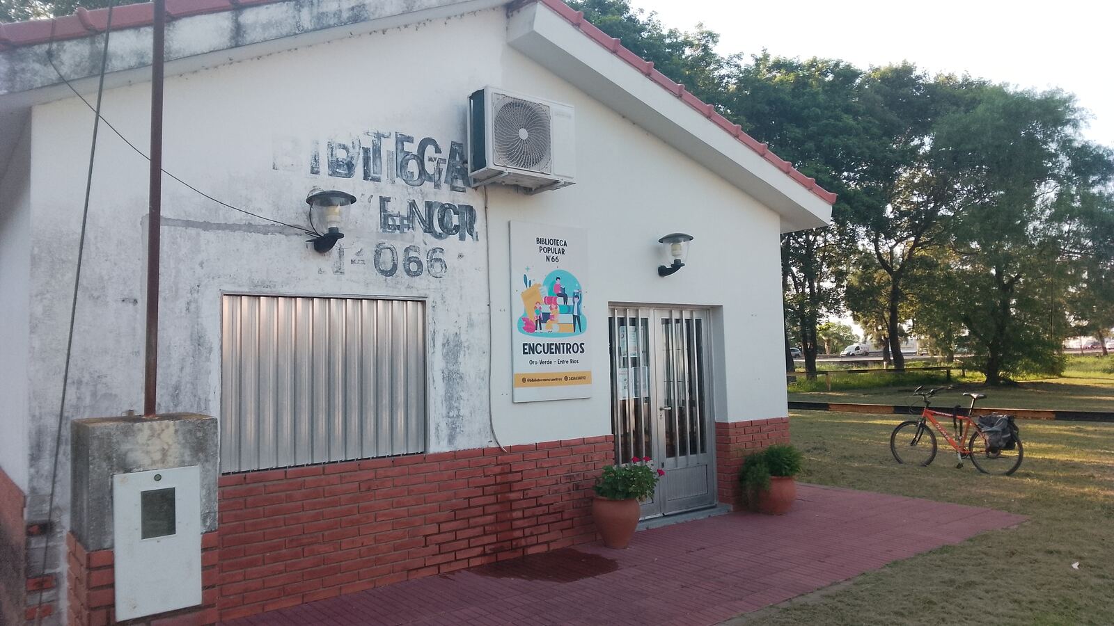 Entrada de la biblioteca, con macetas y bicicleta